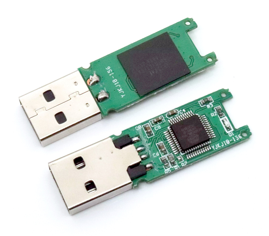 Otvorený USB kľúč z oboch strán. Na jednej strane vidieť malý čip obslužného radiča, na druhej strane dátový NAND flash čip